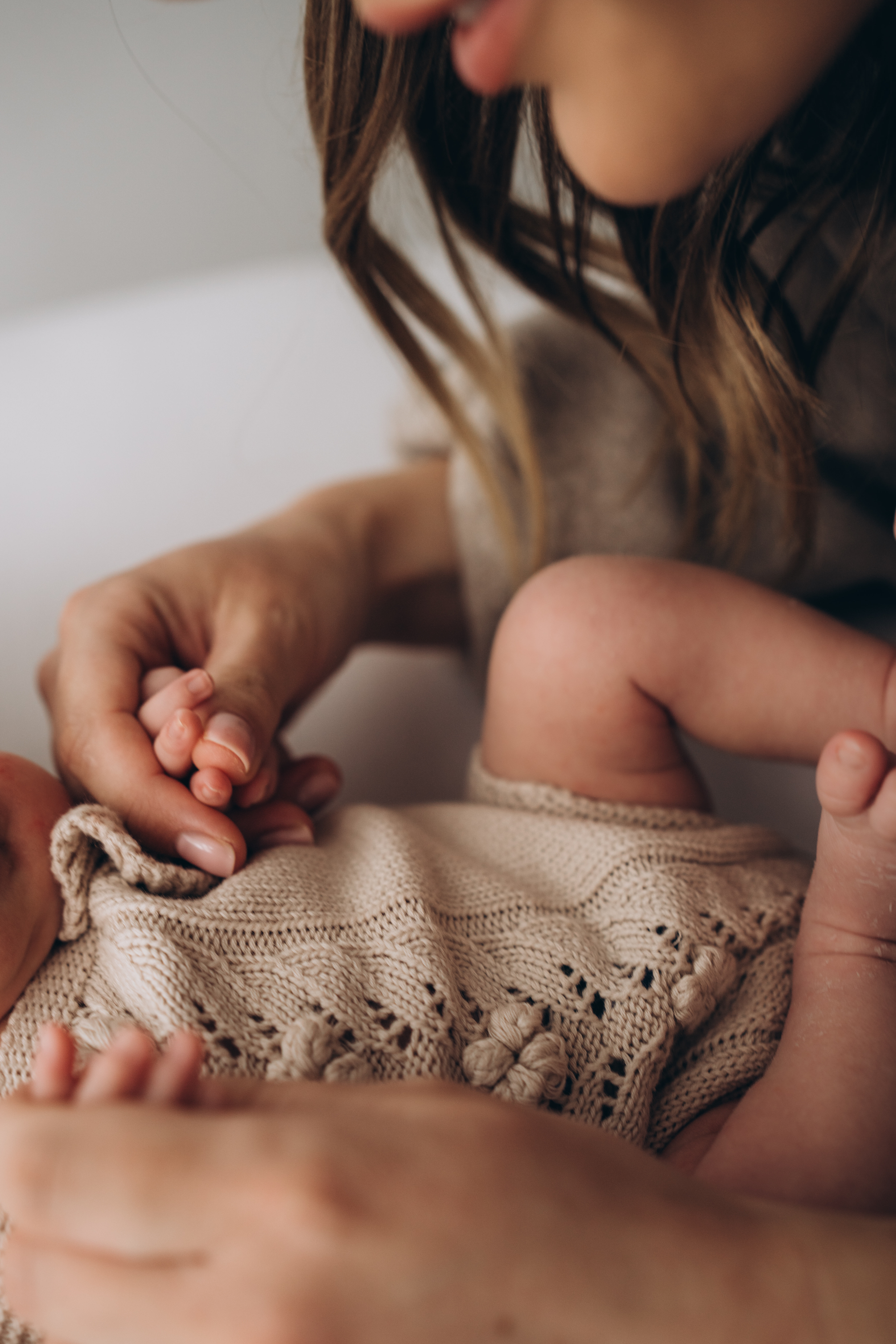 Mama hält die Hand ihres Neugebornen Babys 